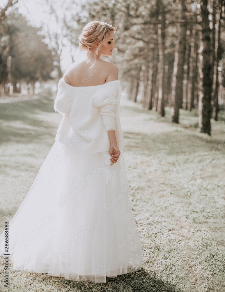 Beautiful blonde bride with stylish make-up in white dress in spring garden 