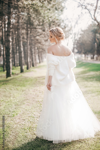 Beautiful blonde bride with stylish make-up in white dress in spring garden 