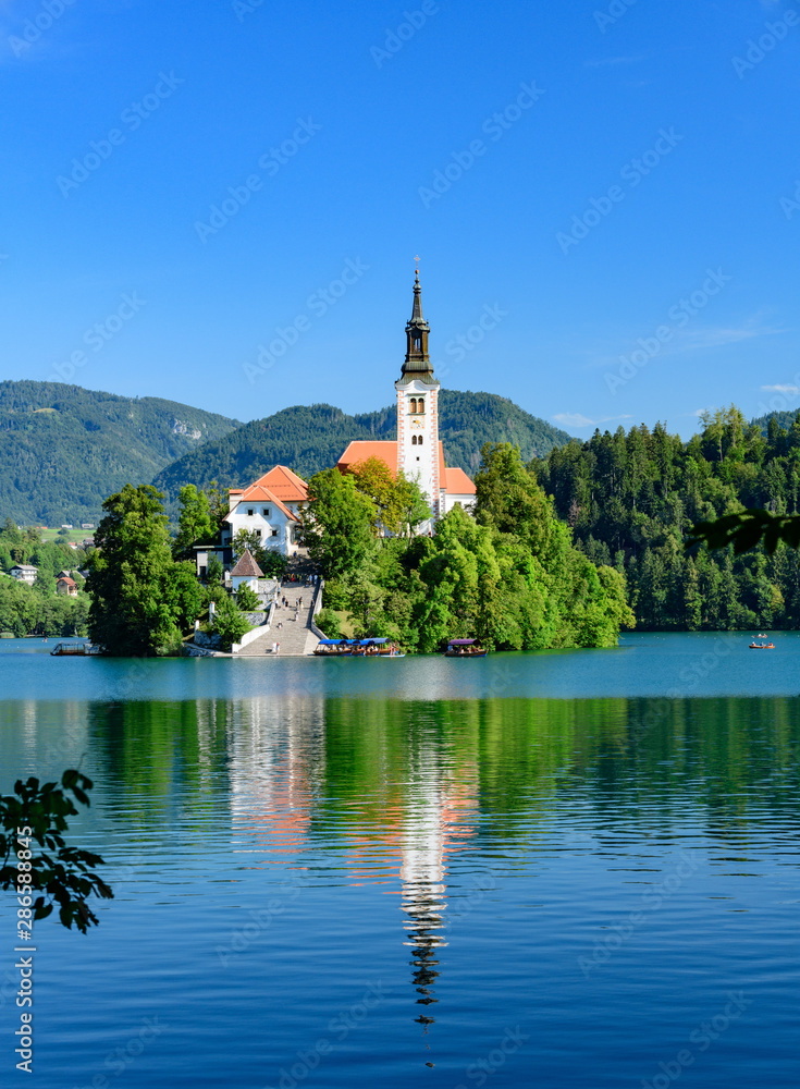 Picturesque view of the island on Lake Bled with Pilgrimage Church of the Assumption of Maria with reflection.