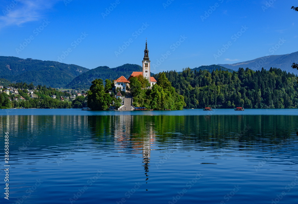 Picturesque view of the island on Lake Bled with Pilgrimage Church of the Assumption of Maria with reflection.