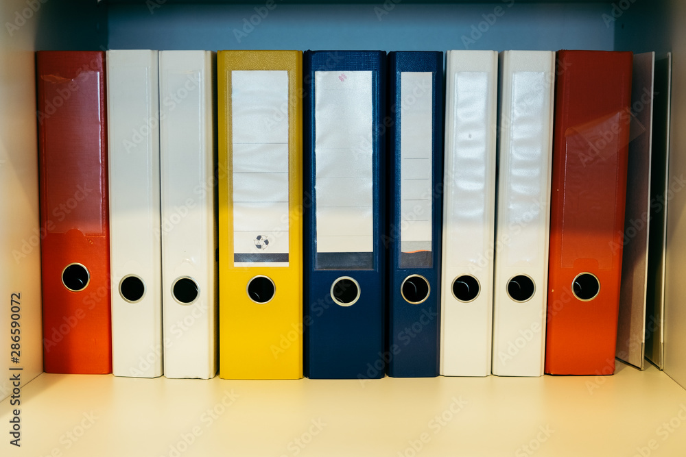 Colorful binders on a shelf with empty labels Colorful binders on a shelf with empty labels
