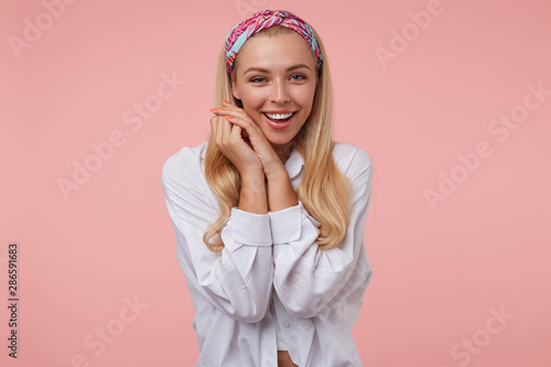 Fototapeta Indoor shot of young attractive woman with crossed palms near her face looking t