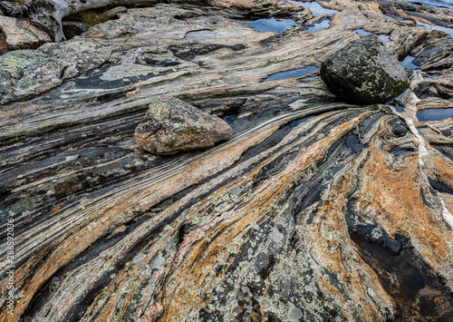 Boulders lying on slab of multi-banded gneiss along the shore of an island in the 30,000-island region of the Georgian Bay, Canada.   photo