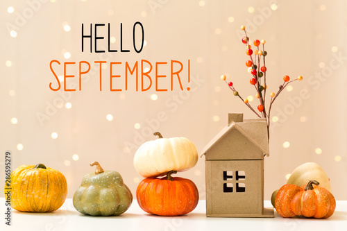 Hello September message with collection of autumn pumpkins with a toy house