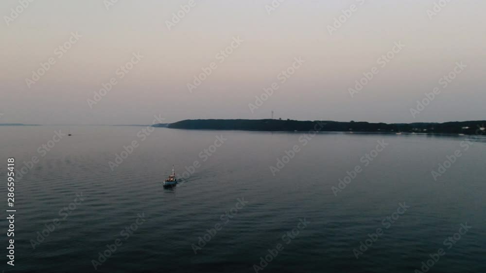 Small Fishing Boat driving back to the port into the sunset. Aerial Smooth Motion. 4K Aerial Boat Stock Footage. Small Fishing Boat driving back to the port into the sunset. Aerial Smooth Motion. 4K Aerial Boat Stock Footage.