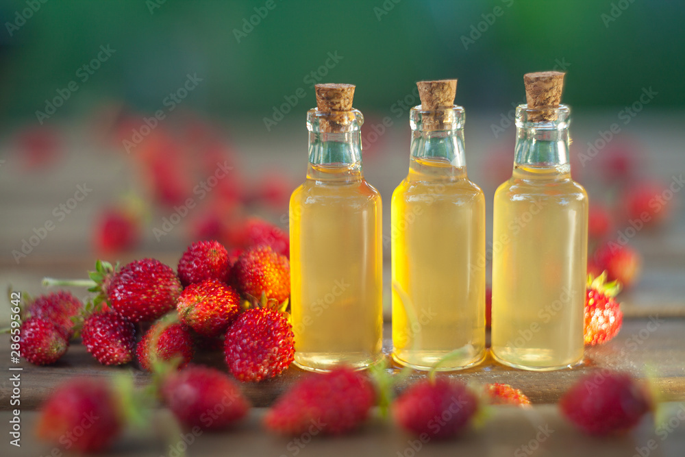 Essence of Wild strawberry on table in beautiful glass jar Essence of Wild strawberry on table in beautiful glass jar