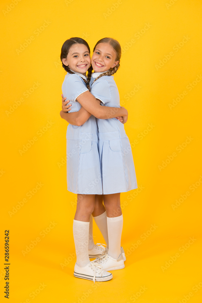 old school. kid fashion. happy friends embrace on yellow background. fashion beauty. childhood happiness. sisterhood of small girls in retro school uniform. children in vintage style. love embrace old school. kid fashion. happy friends embrace on yellow background. fashion beauty. childhood happiness. sisterhood of small girls in retro school uniform. children in vintage style. love embrace