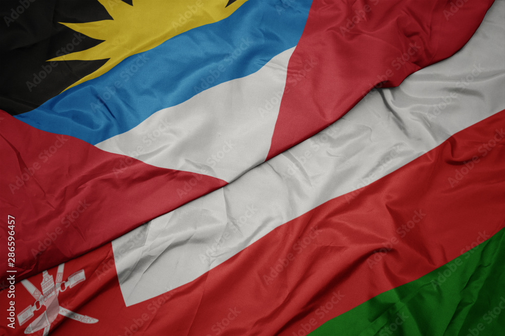 waving colorful flag of oman and national flag of antigua and barbuda.