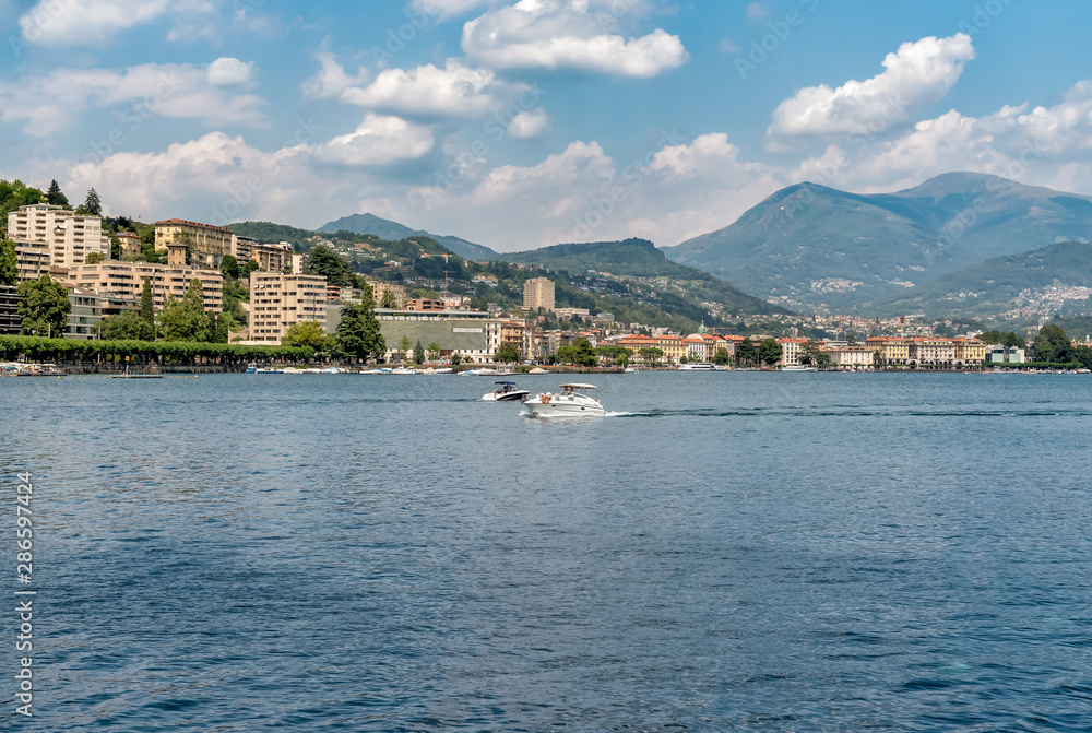 Landscape of Lake Lugano with Lugano city on background in summer day.