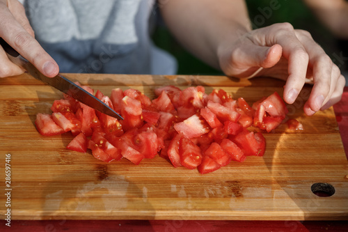female hands cut tomatoes on the board. nature food concept