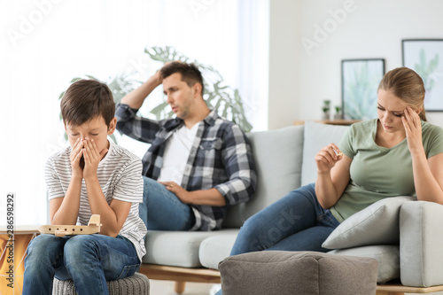 Sad little boy and his quarreled parents at home © Pixel-Shot