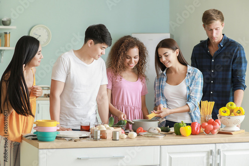 Happy friends cooking together in kitchen