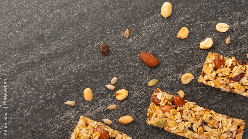 Fototapeta premium granola bars with nuts on a dark background with space for design, horizontal photo, diet, proper nutrition