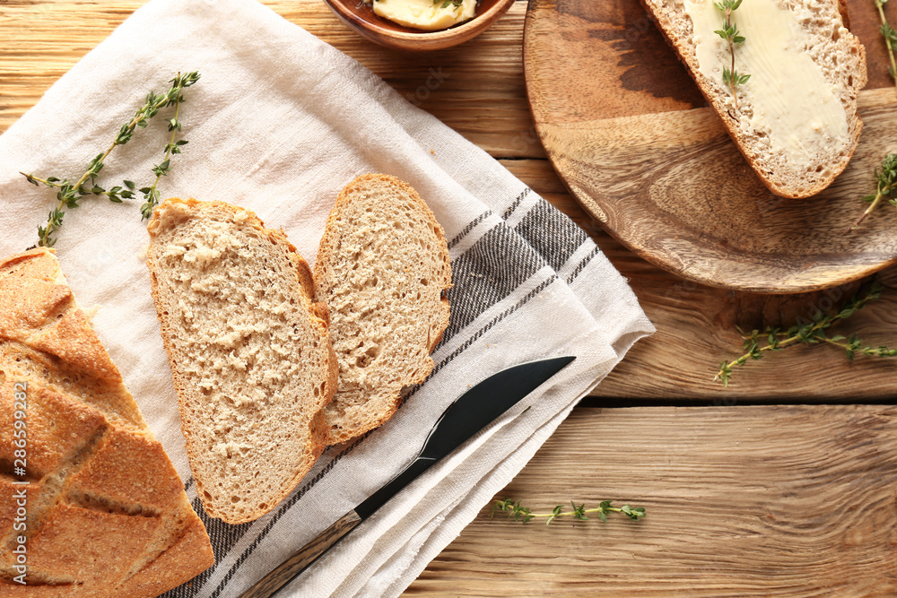 Fresh bread with butter and herbs on wooden table Fresh bread with butter and herbs on wooden table