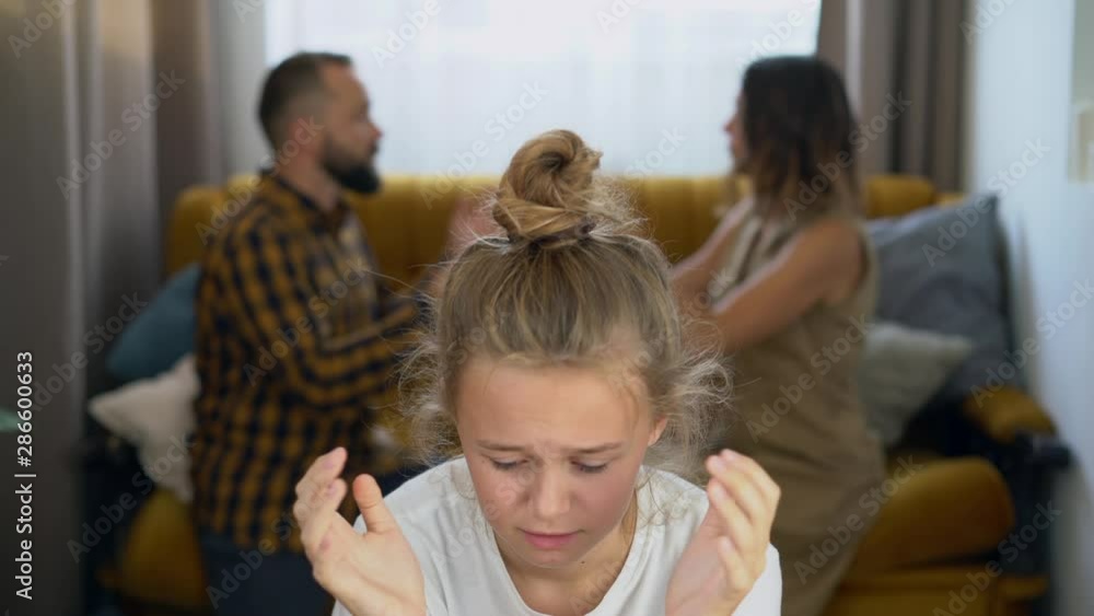 Family portrait A woman is arguing with her husband the girl is sitting and sad Family Conflict. Clarification of relationships. Husband and wife swear Teenager world Family portrait A woman is arguing with her husband the girl is sitting and sad Family Conflict. Clarification of relationships. Husband and wife swear Teenager world