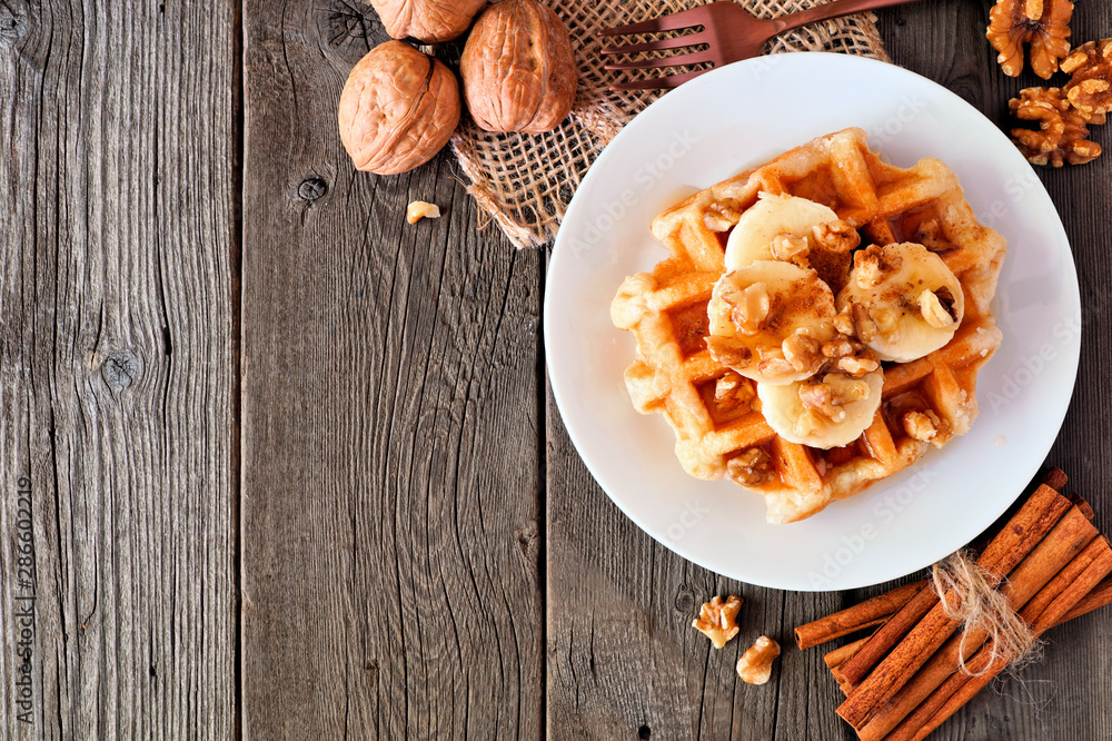 Breakfast waffle with bananas, walnuts and syrup. Top view corner border with copy space over a wood background. Breakfast waffle with bananas, walnuts and syrup. Top view corner border with copy space over a wood background.