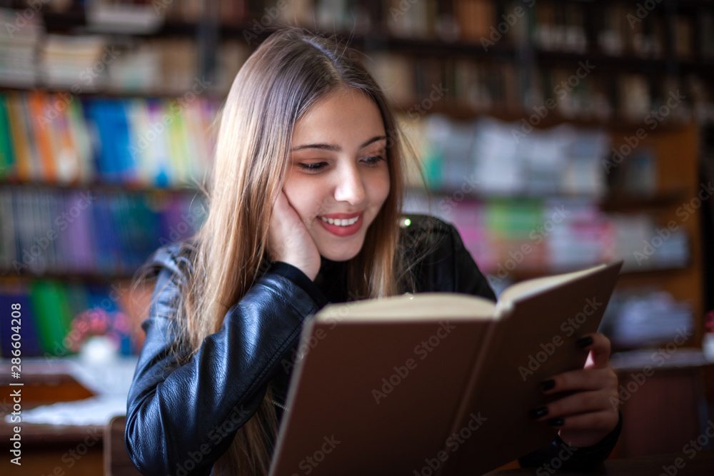 Beautiful teenager schoolgirl sitting in the library and reading a book Beautiful teenager schoolgirl sitting in the library and reading a book