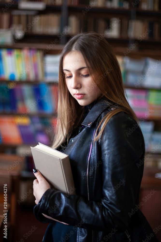 Beautiful teenager schoolgirl reading a book in the library Beautiful teenager schoolgirl reading a book in the library
