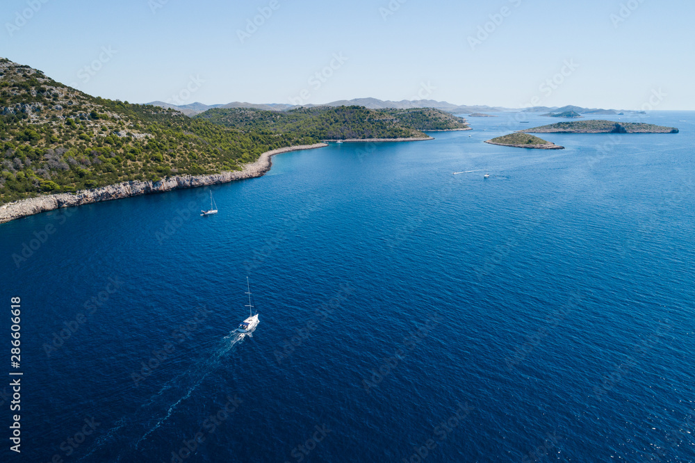 Yacht sailing on the Adriatic sea, cliffs of National park Telascica in background, Croatia