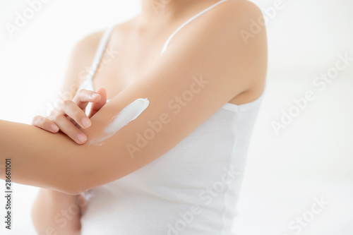 Closeup beautiful young asian woman smile applying sunscreen cream lotion on skin care at bedroom, beauty asia girl makeup and cosmetic for smooth and silky, wellness and health concept. © N_studio