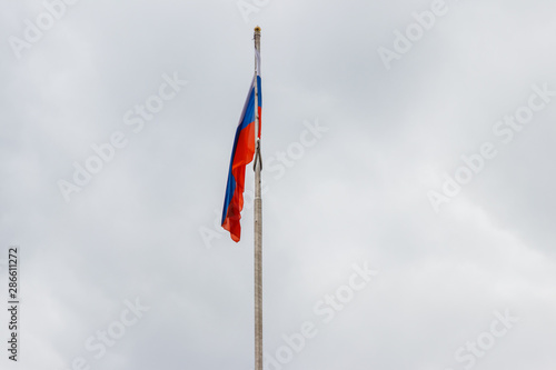 Waving flag of Russia against gloomy cloudy sky
