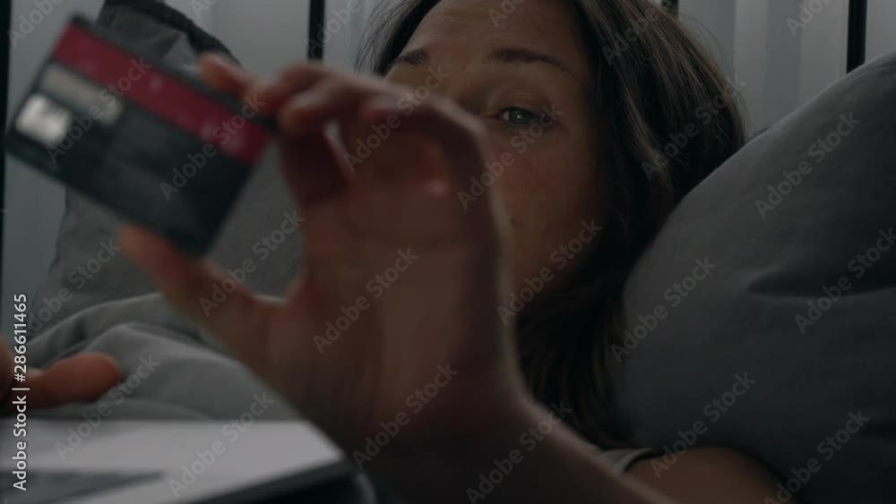 woman with laptop and credit card at home. Girl with laptop and bank card indoors. Beautiful woman lying in the living room shopping online with credit card. Easy pay using digital gadget.
