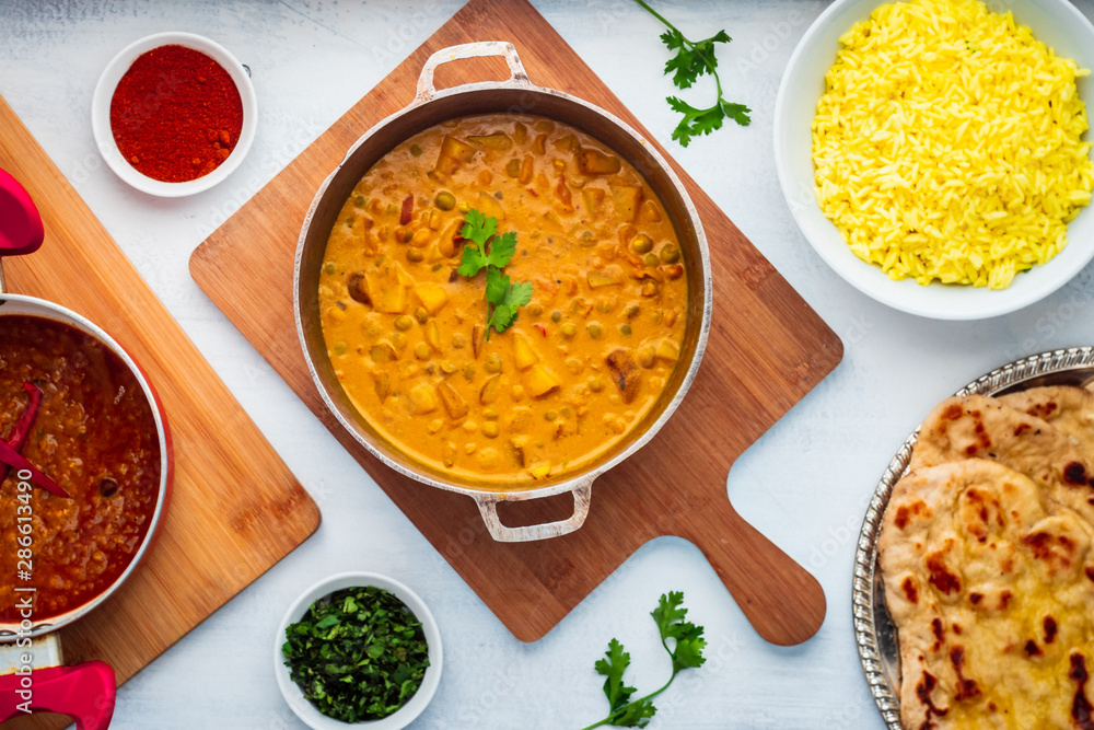 Indian Food: Curry Pot Full of Pea and Potato with Rice Bowl, Dal Pot, Naan Bread and Spices. Indian Food: Curry Pot Full of Pea and Potato with Rice Bowl, Dal Pot, Naan Bread and Spices.