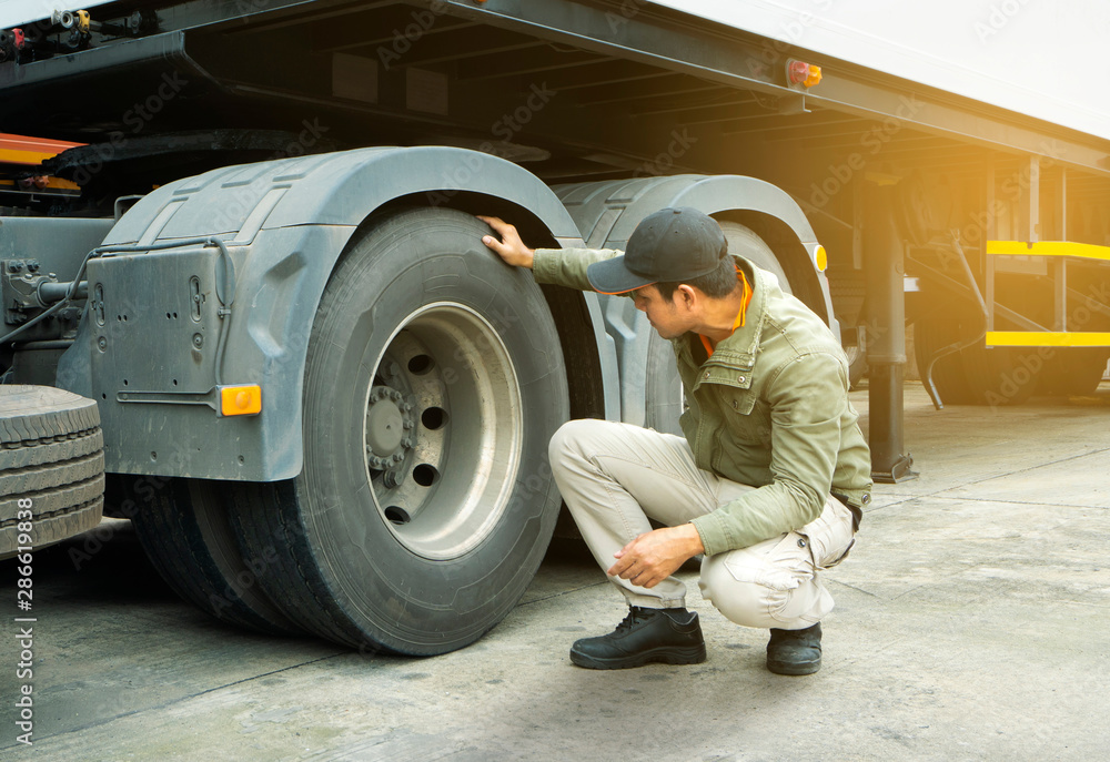 truck driver inspecting safety check of a truck tires.
