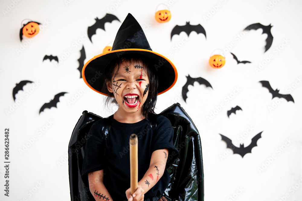 Cute asian child girl wearing halloween costumes and makeup having fun on Halloween celebration