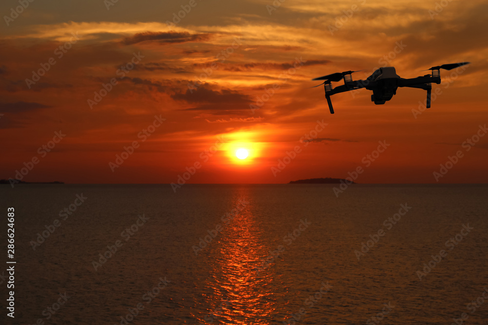 Drones while flying in the sky at sunset, Ocean and island backgrounds. Drones while flying in the sky at sunset, Ocean and island backgrounds.