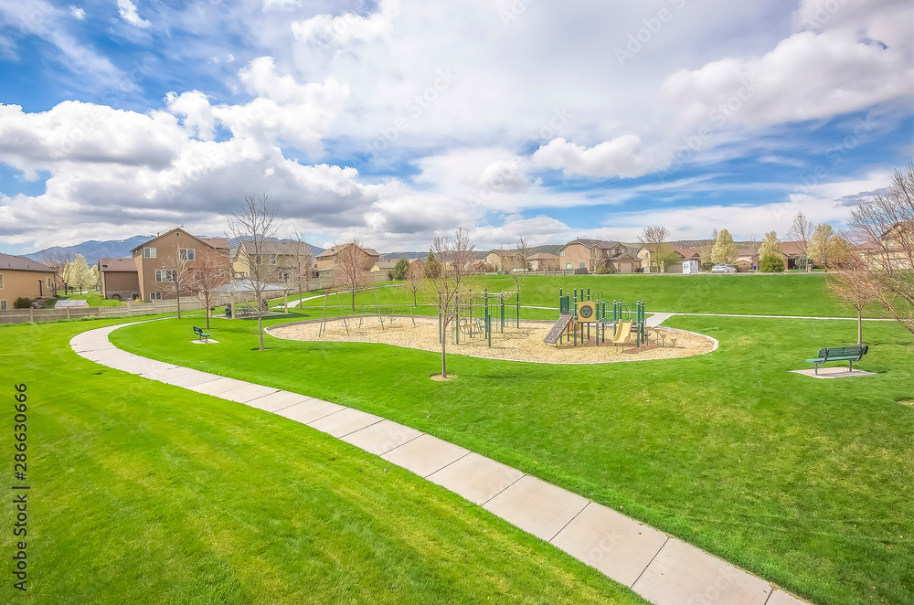 Scenic view of park and houses on a residential area under cloudy blue sky