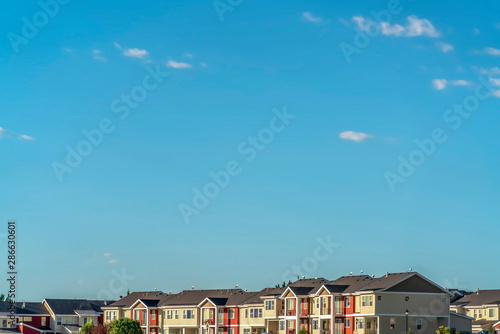 Blue sky on a sunny day over townhomes with white and red exterior wall