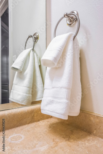Close up of a white towel hanging on a metal ring mounted on the bathroom wall