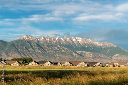 Magnificent mountain towering over homes and vast grassy terrain on a sunny day photo