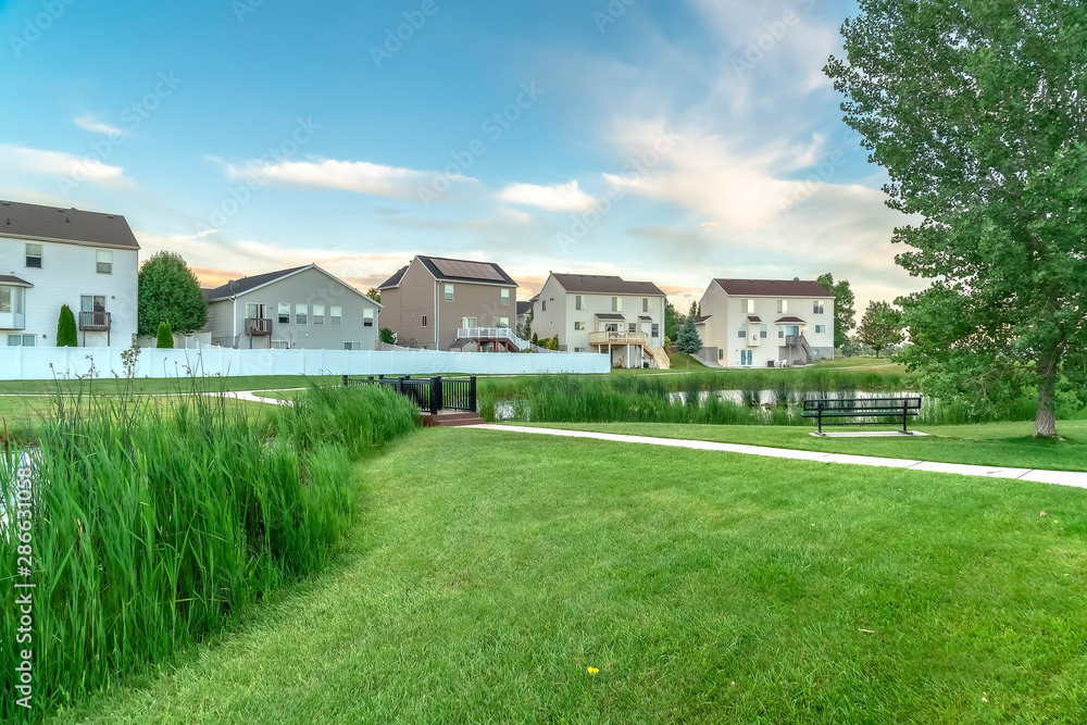 Scenic nature view with park in front of houses under cloudy sky on a sunny day