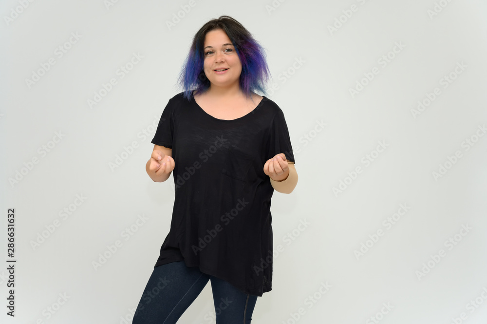 Stock Foto Portrait of a knee-deep funny cheerful girl of a young woman with multi-colored hair in a black T-shirt on a white background. In the studio, smiling, talking. Stock Foto Portrait of a knee-deep funny cheerful girl of a young woman with multi-colored hair in a black T-shirt on a white background. In the studio, smiling, talking.