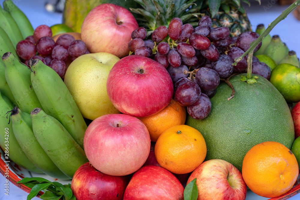 Assortment of fresh fruit banana, grapes, orange, apple, pineapple, tangerine and grapefruit on a tray. Closeup