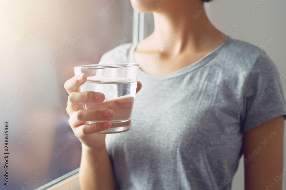 young woman standing and holding glass water near window. concept healthy young woman standing and holding glass water near window. concept healthy