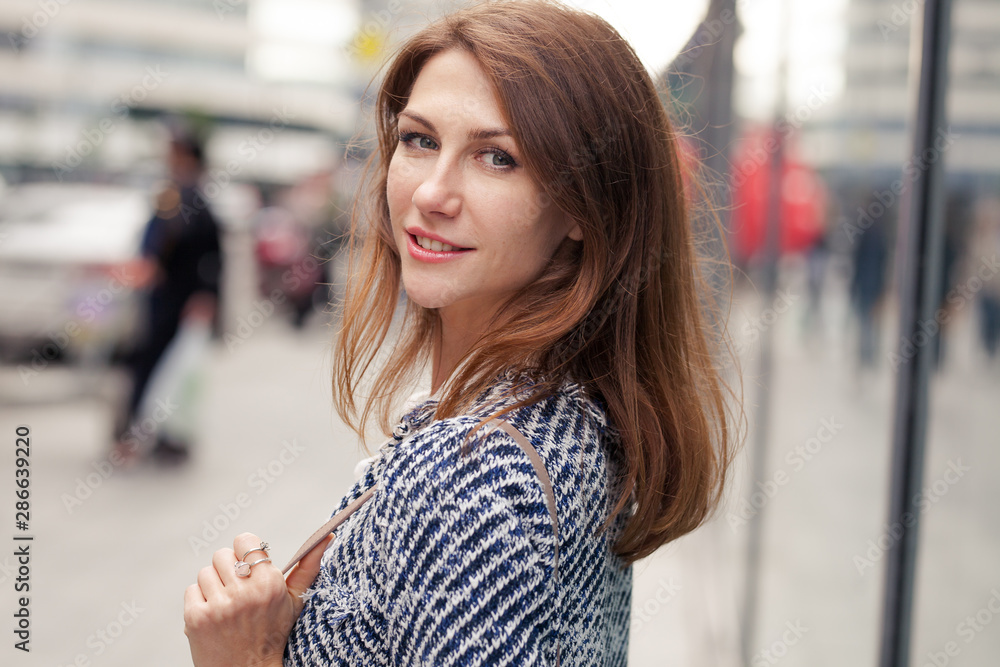 Portrait of beautiful young business woman in elegant clothes stands outdoors on the street in city center Portrait of beautiful young business woman in elegant clothes stands outdoors on the street in city center