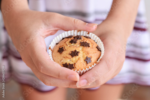 Closeup of girl holding delicious homemade vanilla muffins whit chocolate chips