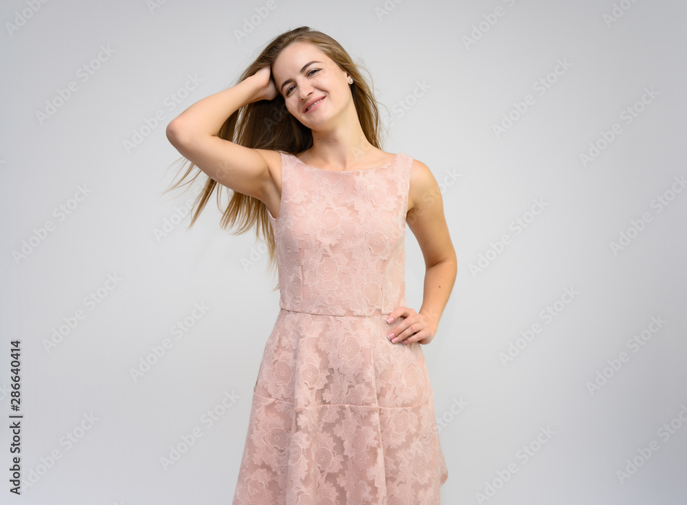 Studio portrait of a knee-length of a pretty girl student, brunette young woman with long beautiful hair in a pink dress on a white background. Smiling, talking, showing emotions Studio portrait of a knee-length of a pretty girl student, brunette young woman with long beautiful hair in a pink dress on a white background. Smiling, talking, showing emotions
