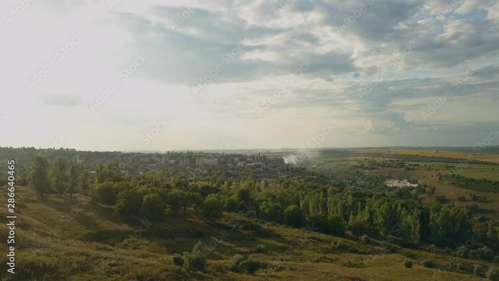 Top view drone flight over green fields and suburbs at sunset. Summer landscape Top view drone flight over green fields and suburbs at sunset. Summer landscape
