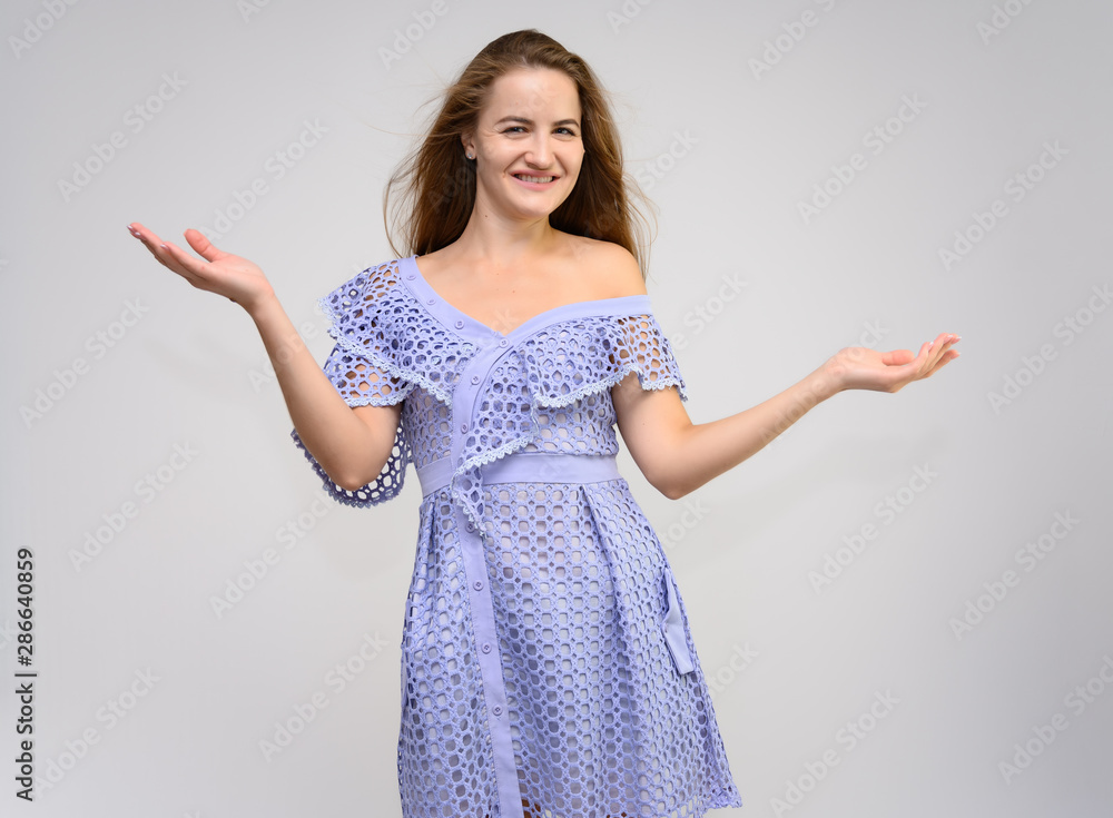 Studio portrait of a knee-length of a pretty girl student, brunette young woman with long beautiful hair in a dress on a white background. Smiling, talking, showing emotions Studio portrait of a knee-length of a pretty girl student, brunette young woman with long beautiful hair in a dress on a white background. Smiling, talking, showing emotions