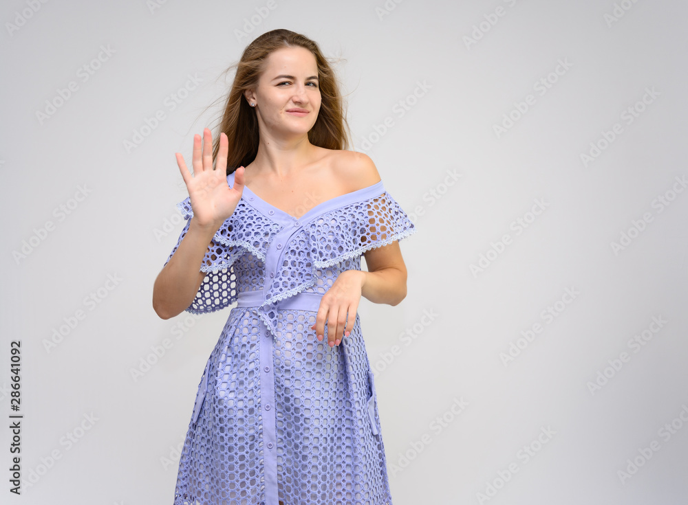 Studio portrait of a knee-length of a pretty girl student, brunette young woman with long beautiful hair in a dress on a white background. Smiling, talking, showing emotions Studio portrait of a knee-length of a pretty girl student, brunette young woman with long beautiful hair in a dress on a white background. Smiling, talking, showing emotions