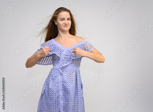Studio portrait of a knee-length of a pretty girl student, brunette young woman with long beautiful hair in a dress on a white background. Smiling, talking, showing emotions photo