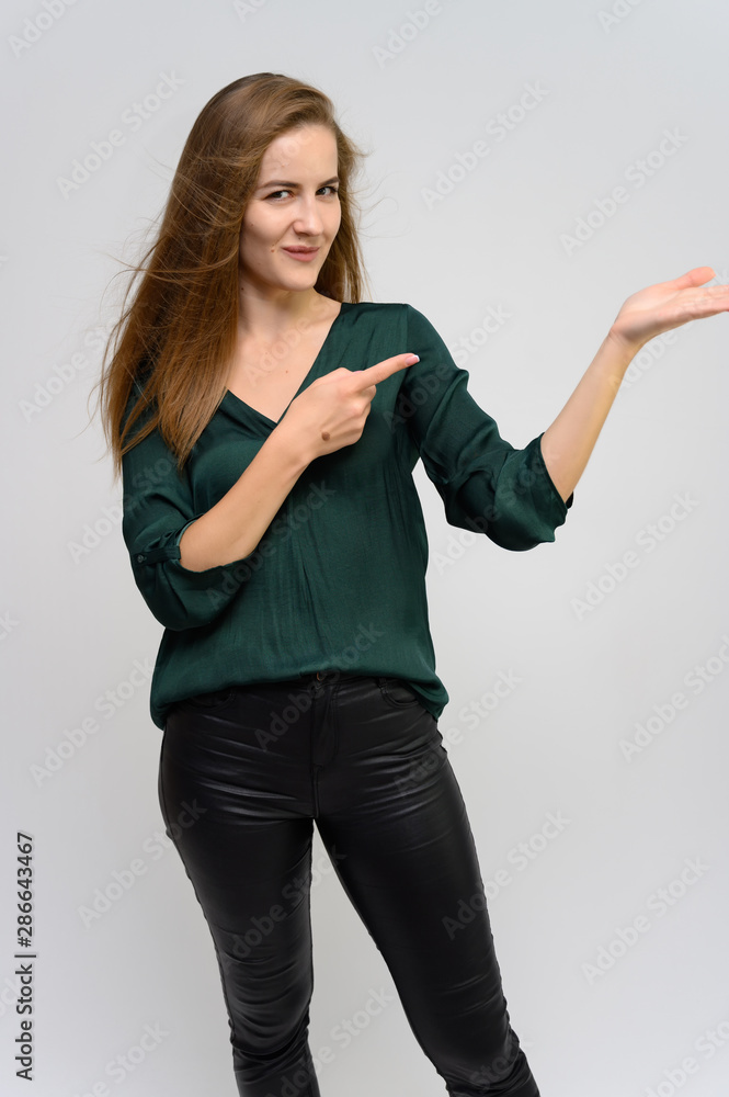 Studio portrait of a knee-length of a pretty student girl, a young brunette woman with long beautiful hair in a green blouse and black pants on a white background. Smiling, talking, showing emotions Studio portrait of a knee-length of a pretty student girl, a young brunette woman with long beautiful hair in a green blouse and black pants on a white background. Smiling, talking, showing emotions
