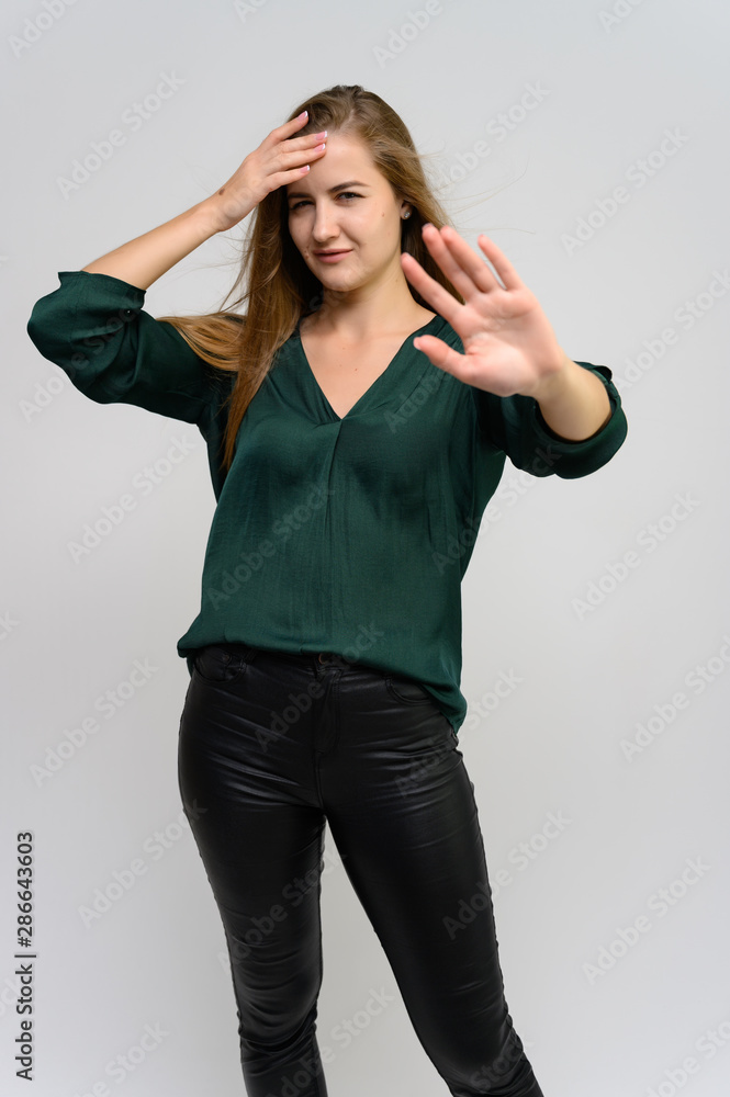Studio portrait of a knee-length of a pretty student girl, a young brunette woman with long beautiful hair in a green blouse and black pants on a white background. Smiling, talking, showing emotions Studio portrait of a knee-length of a pretty student girl, a young brunette woman with long beautiful hair in a green blouse and black pants on a white background. Smiling, talking, showing emotions