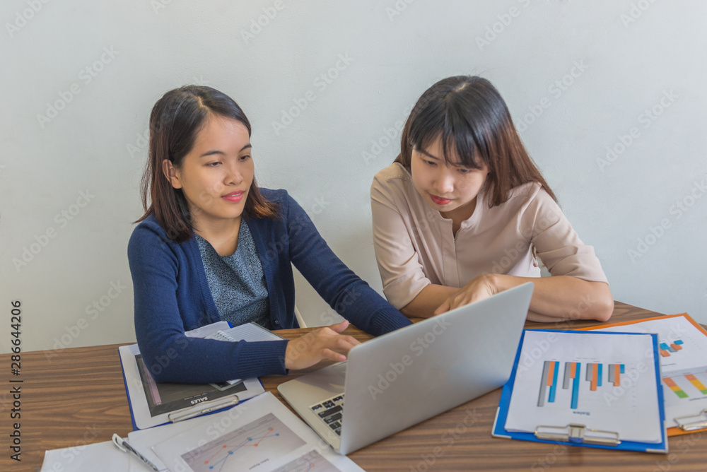 Young female financial advisor working on laptop and statistics paperworks Young female financial advisor working on laptop and statistics paperworks