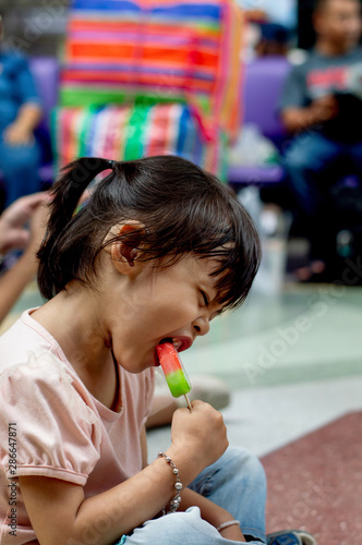 Little asian child girl eating ice cream.