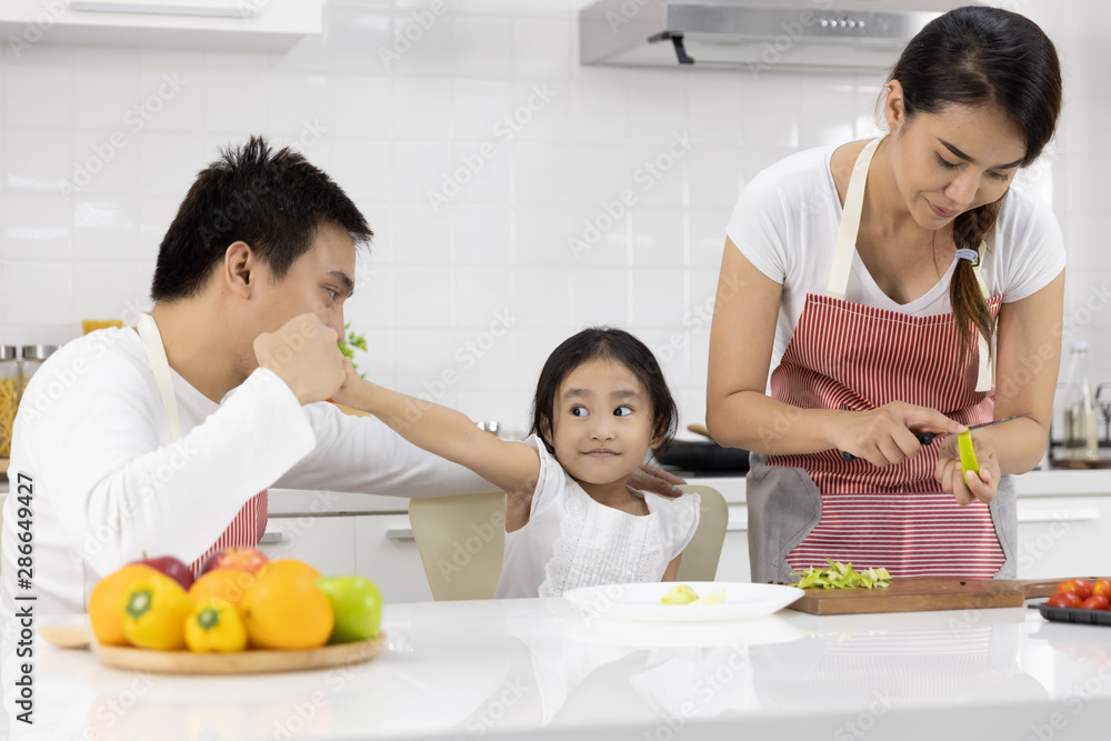 Happy Asian family make a cooking. Father, Mother and Daughter are preparing fruit, green apple in the kitchen at home. Healthy food concept and happy holidays Happy Asian family make a cooking. Father, Mother and Daughter are preparing fruit, green apple in the kitchen at home. Healthy food concept and happy holidays